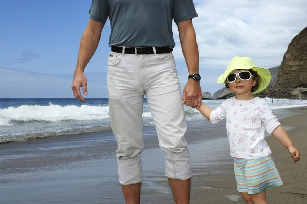Gelukkig meisje bezit is van iemands hand op een strand — Stockfoto