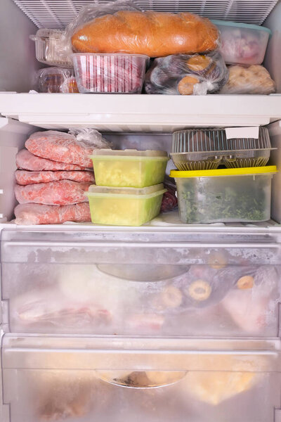 Много различных замороженных сырых продуктов в контейнерах в домашней морозильной камере, мясо, овощи, хлеб и полуфабрикаты, кухонные запасы.
