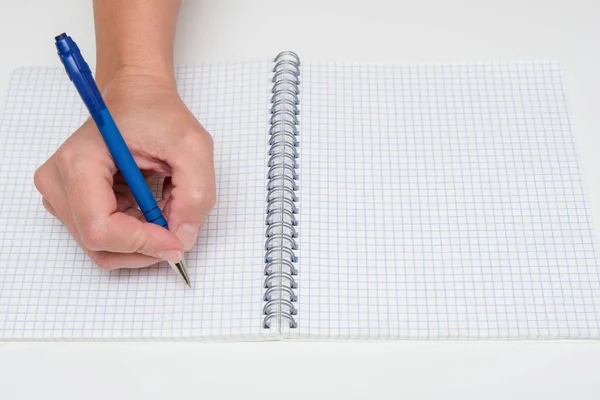 Écriture de notes ou planification d'un horaire sur un cahier spirale vierge, main à l'aide d'un stylo sur un papier blanc à carreaux, espace de copie — Photo