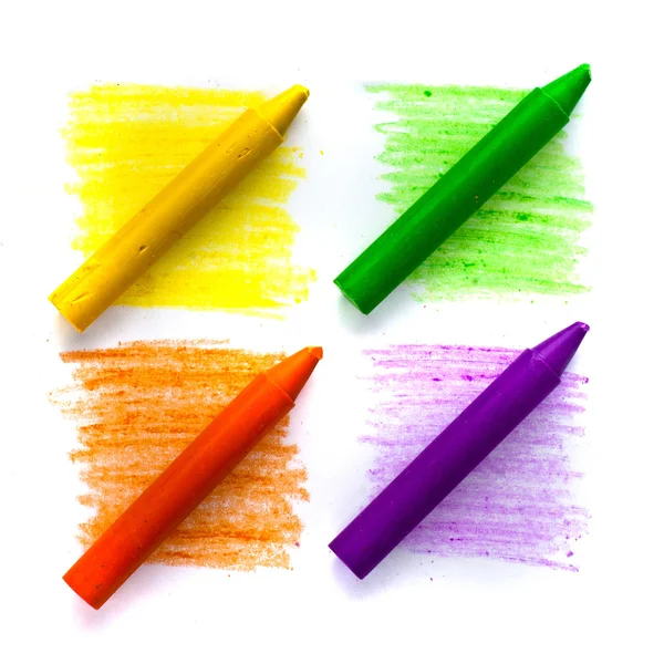 Oil pastel crayons lying on a paper with painted rainbow Stock