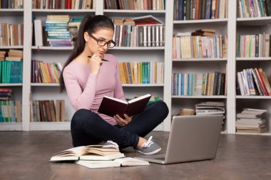 Kütüphanede katta oturan düşünceli genç kadın