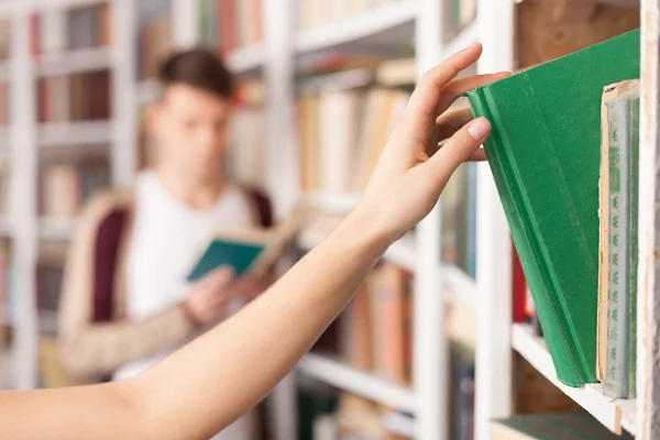 Someone taking a book from the book shelf — Stock Photo, Image