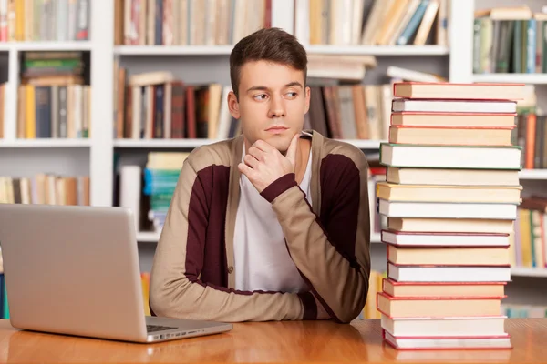 Mylić młody mężczyzna siedzący przy biurku biblioteki — Zdjęcie stockowe