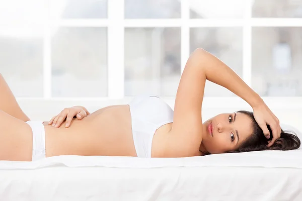 Mujer joven en lencería acostada en la cama — Foto de Stock