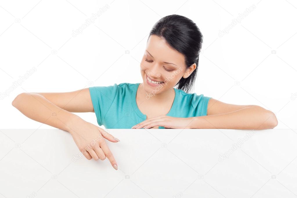 Woman leaning at copy space and pointing at it