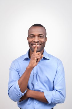 parmağını ağzına tutarak ve gülümseyerek Afrikalı bir adam
