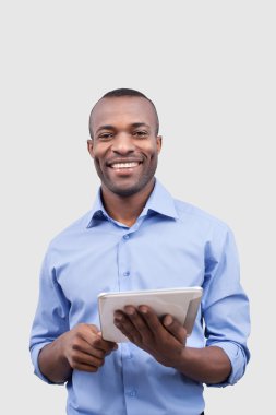 Dijital tablet üzerinde çalışan ve gülümseyerek Afrikalı bir adam