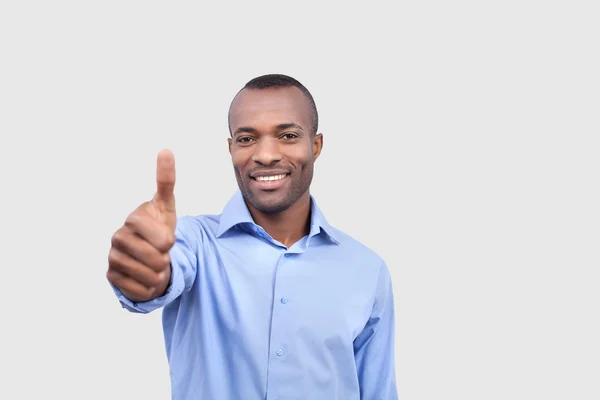 Jovem negro sorrindo e estendendo a mão com o polegar para cima — Fotografia de Stock