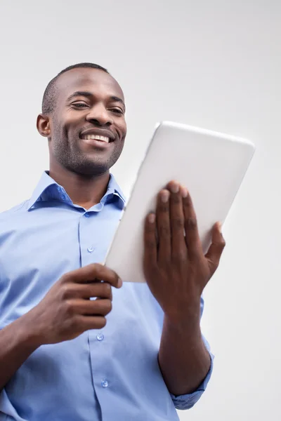 Homem africano trabalhando em tablet digital e sorrindo — Fotografia de Stock