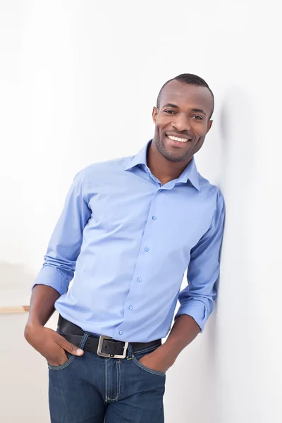 Joven hombre negro apoyado en la pared y sonriendo a la cámara —  Fotos de Stock