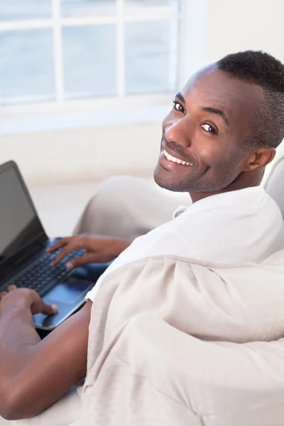 Uomo africano utilizzando il computer e guardando oltre la spalla — Foto Stock