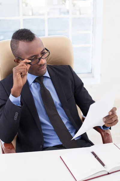 African businessman looking at the paper and adjusting his glasses — Stock Photo, Image