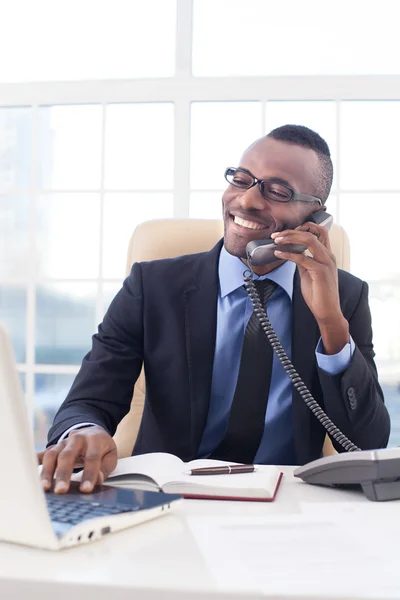 Empresario africano hablando en el teléfono móvil y usando el ordenador — Foto de Stock