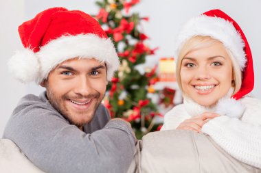 Çift kanepede oturan santa şapkalar