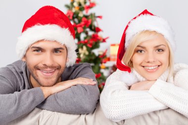 Çift kanepede oturan santa şapkalar