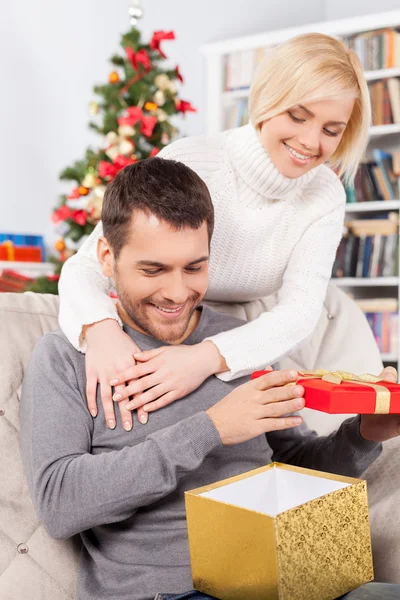 Mann hält eine Geschenkbox, während ihre Freundin hinter ihm steht — Stockfoto