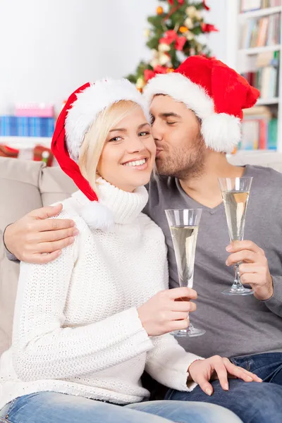 Kvinna med champagne flöjt medan hennes pojkvän kysser hennes kind — Stockfoto