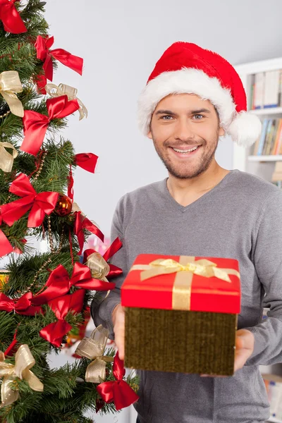 Man holding a gift box near the Christmas tree — Stock Photo, Image