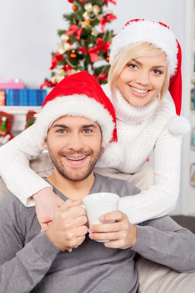 Hombre sentado con la novia sombreros de Navidad y sosteniendo una taza — Foto de Stock