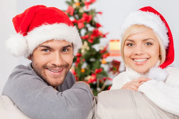 Couple in Santa hats sitting on the couch Stock Image