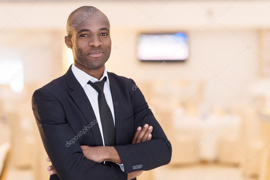 Cheerful young African man in full suit keeping arms crossed