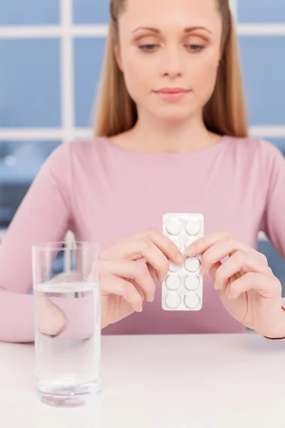 Thoughtful young woman holding medicines — Stock Photo, Image