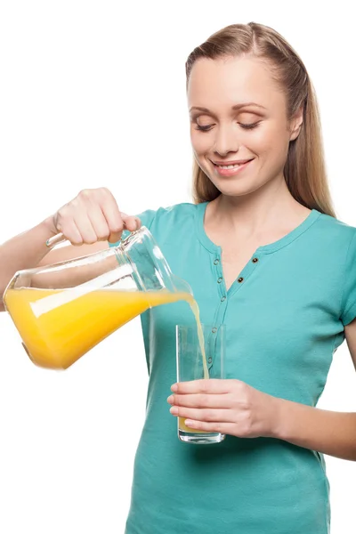 Beautiful young woman pouring juice into glass — Stock Photo, Image