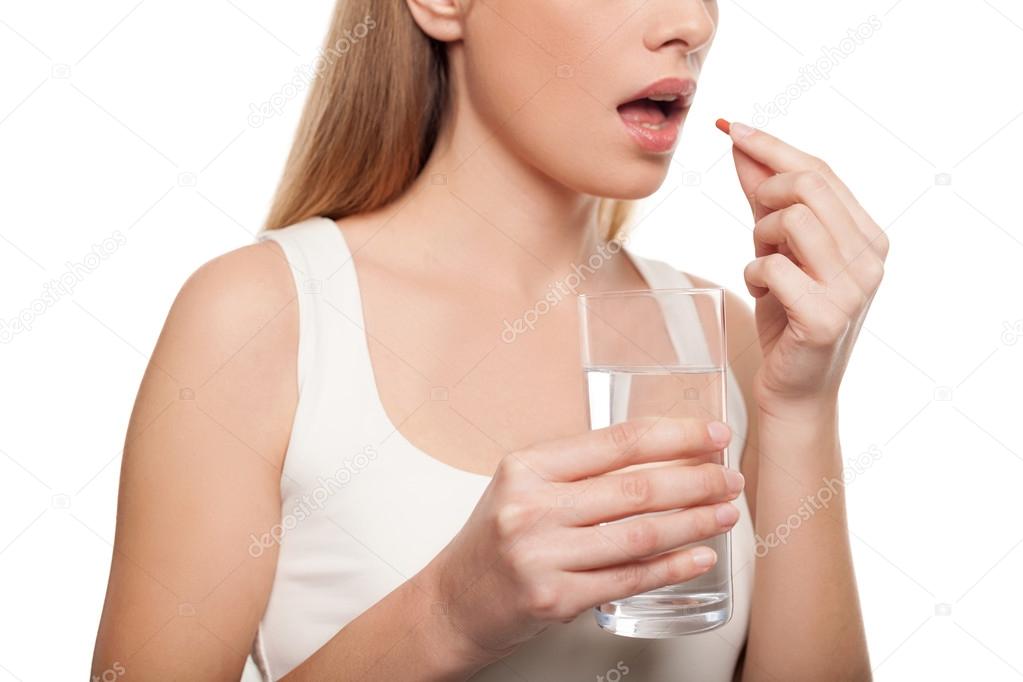 Depressed young woman taking a pill