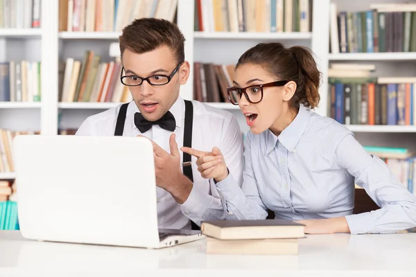 Verrast jonge nerd paar in glazen op zoek op computermonitor — Stockfoto