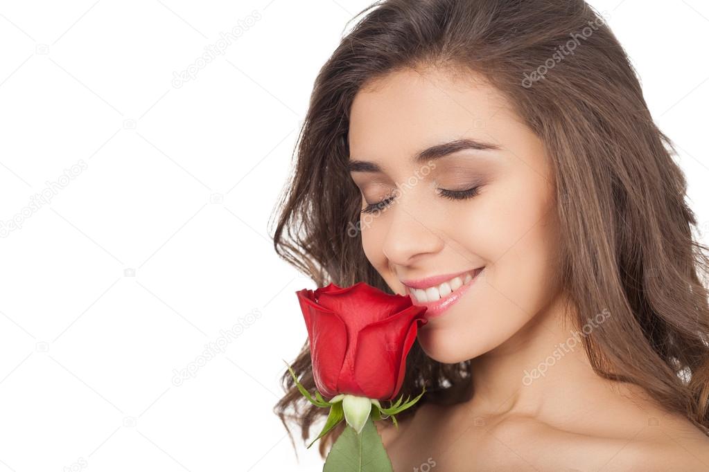 Beautiful young woman holding a red rose near nose