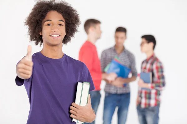 Cheerful African teenage boy holding books and gesturing — Stock Photo, Image