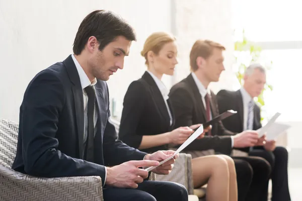 dört kişi sırada bekleyen resmi kıyafeti