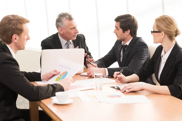 Vier mensen uit het bedrijfsleven in formalwear bespreken iets — Stockfoto