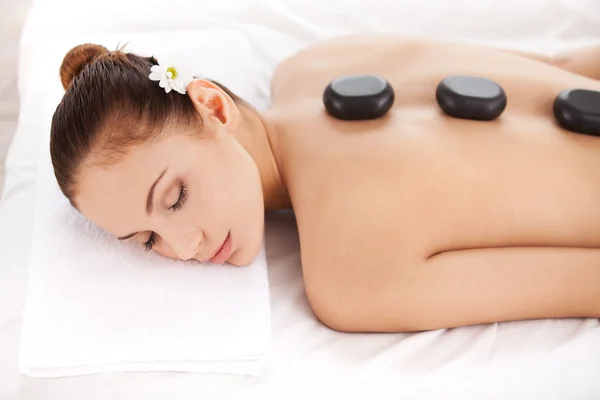 Young woman lying with stones on her back — Stock Photo, Image