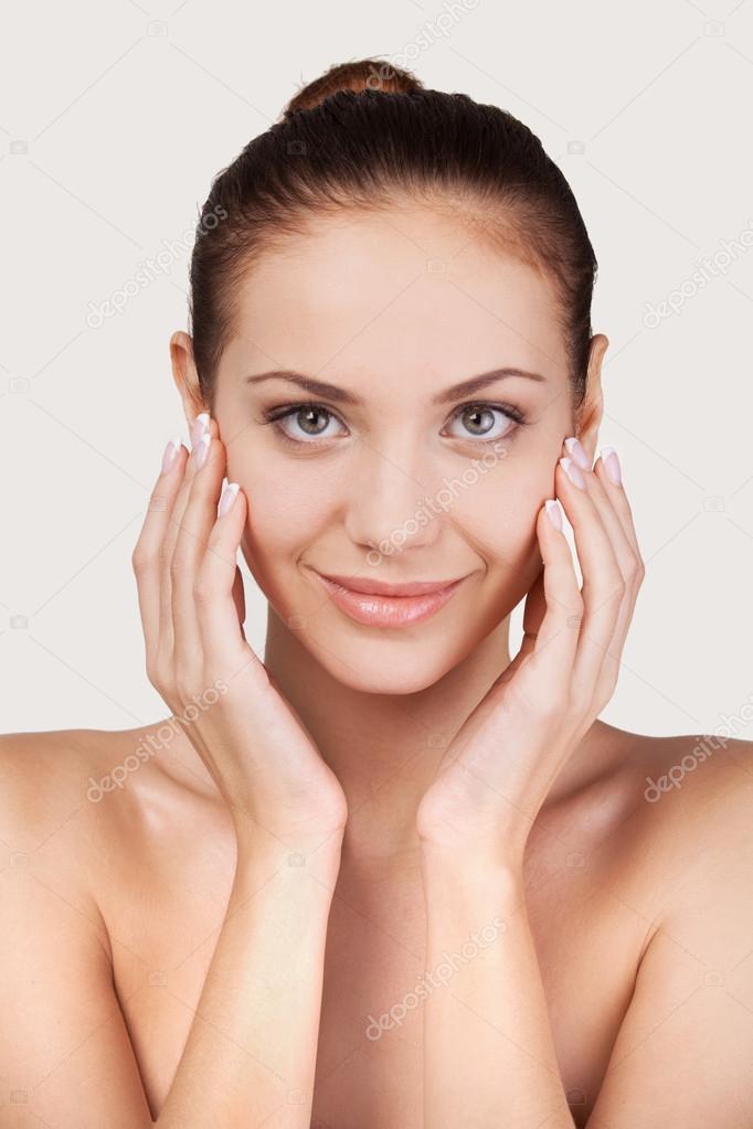 Cheerful young shirtless woman touching face