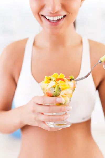 Young woman in sports clothing eating a fruit salad — Stock Photo, Image