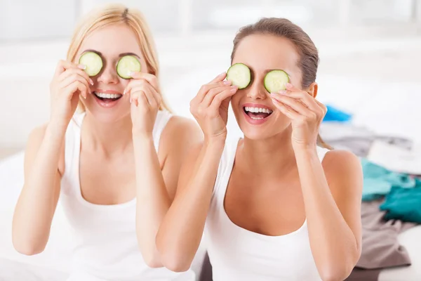 Two beautiful young women holding pieces of cucumber on their eyes — Stock Photo, Image