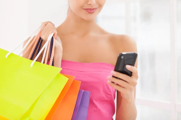 Jonge vrouw met shopping tassen en mobiele telefoon — Stockfoto