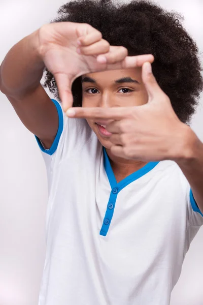 Alegre adolescente africano mirando a través de un marco de dedo —  Fotos de Stock