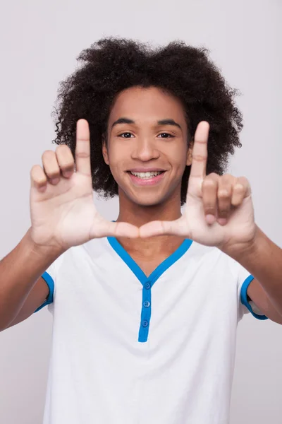 Vrolijke Afrikaanse tiener kijken door een vinger frame — Stockfoto