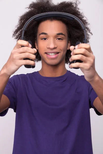 Alegre adolescente africano sosteniendo auriculares — Foto de Stock