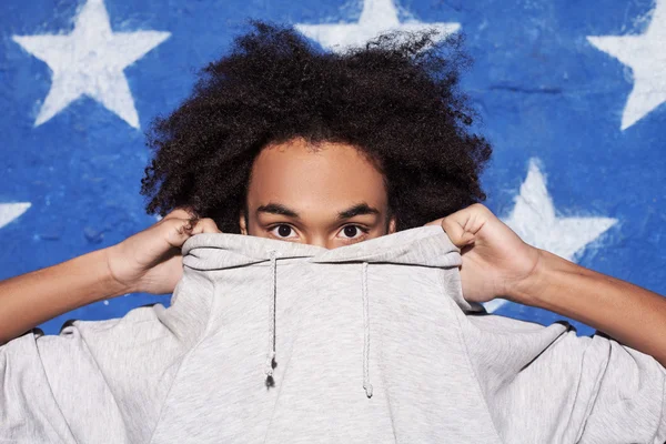 Cool and young. Teenage African boy hiding his face in his clothing — Stock Photo, Image