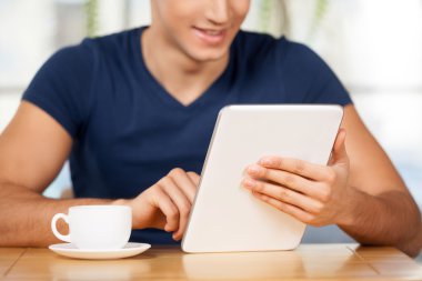 Man using digital tablet while sitting at the restaurant clipart