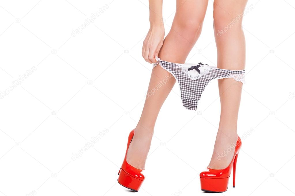 Close-up cropped image of woman in red high heeled shoes taking off her pan...