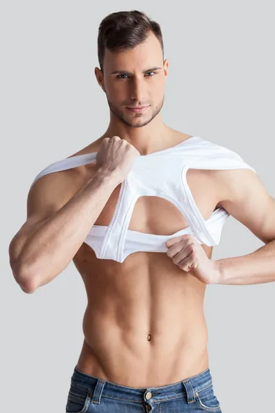 Muscular man taking off tank top — Stock Photo, Image