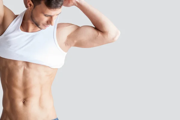 Muscular man taking off tank top — Stock Photo, Image