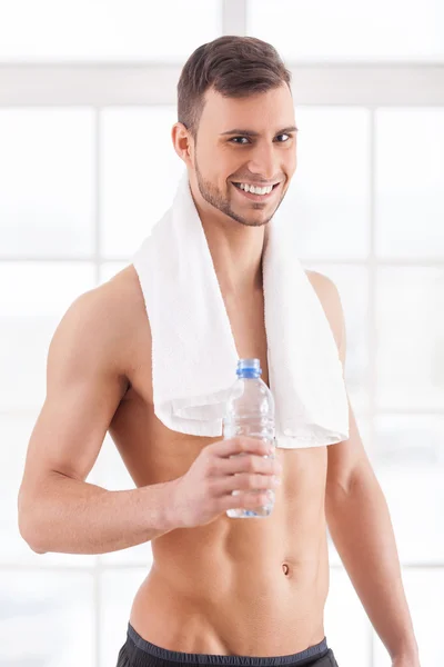 Muscular man with towel holding a bottle — Stock Photo, Image