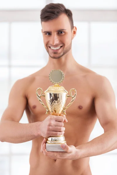 Muscular man holding a golden trophy — Stock Photo, Image