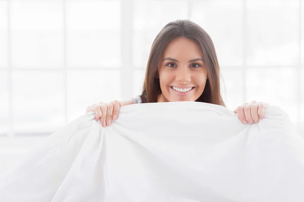 Jonge vrouw kijken uit de deken — Stockfoto