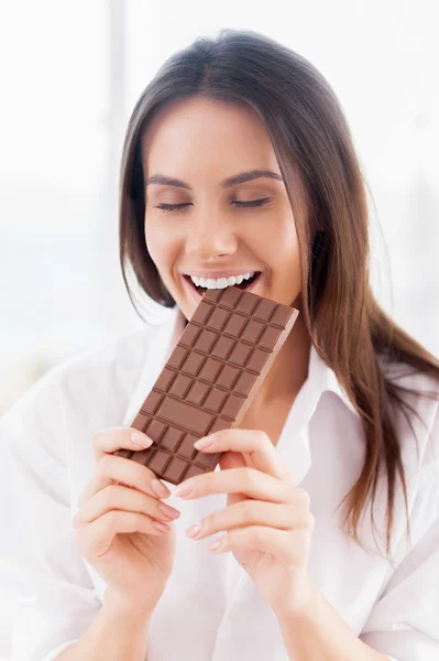 Vrouw in wit overhemd eten van chocolade — Stockfoto